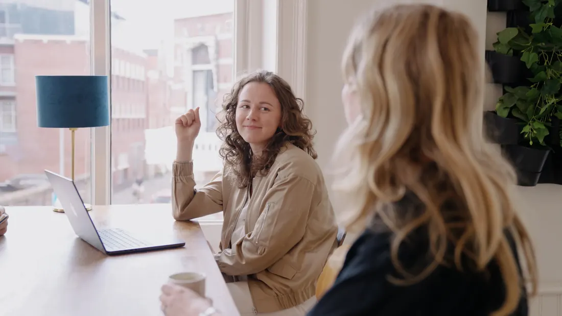 Aniek en Lotte in gesprek aan tafel op kantoor
