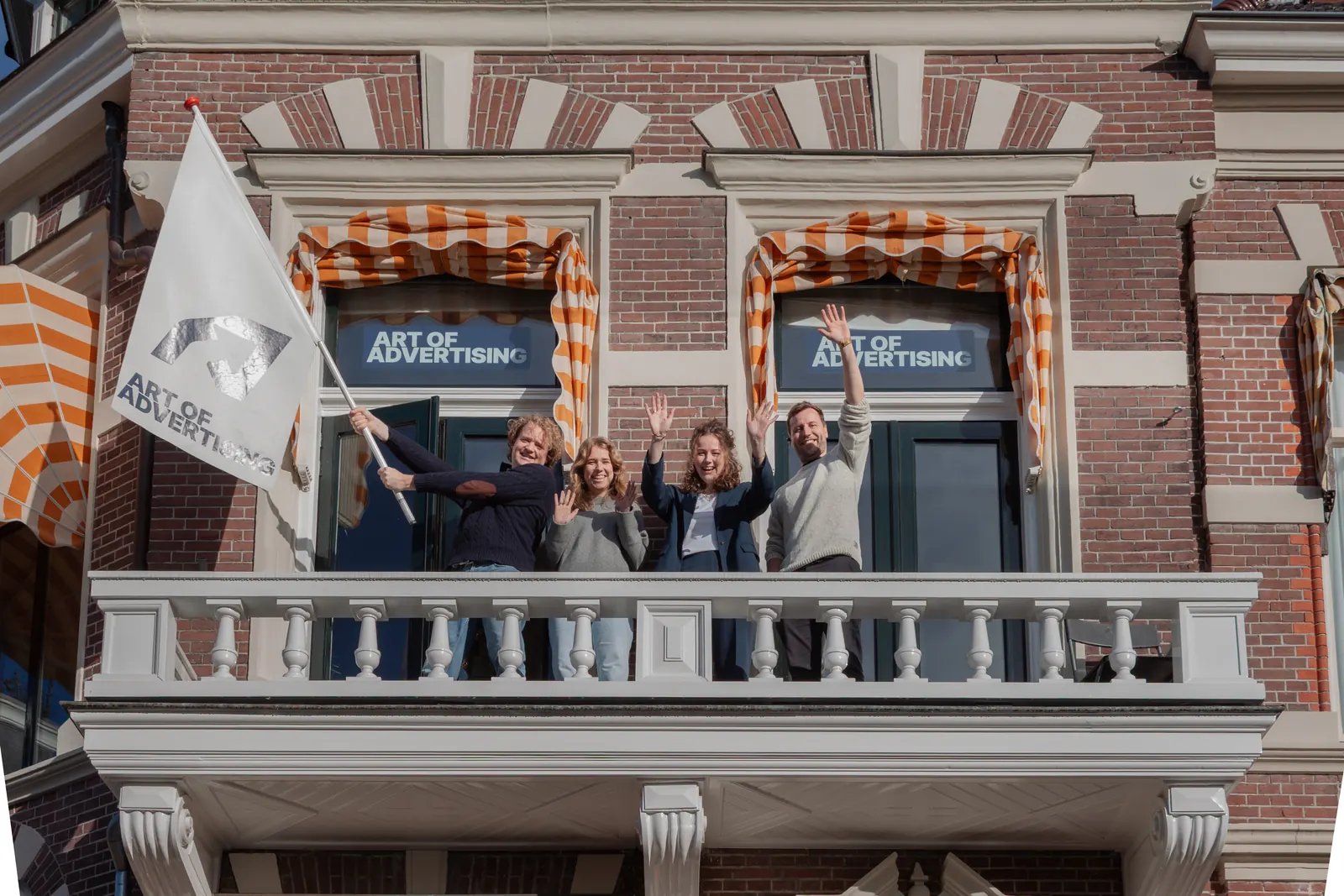 Het team zwaait vanaf het balkon van het kantoor aan de Coehoornsingel in Groningen